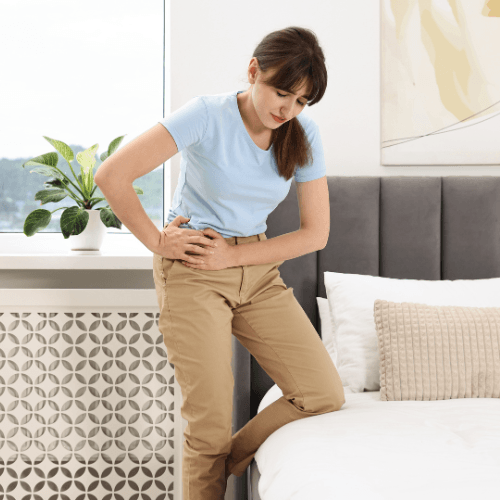 Woman holding the front of her hip indicating pain from iliopsoas tendinopathy.