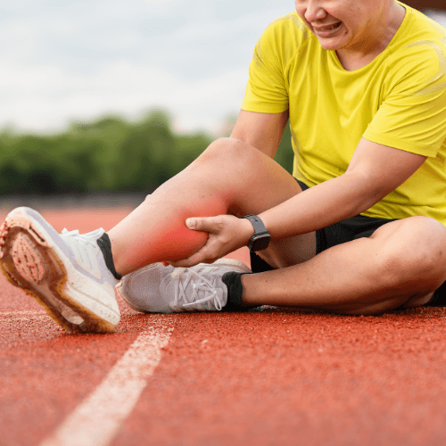 Athlete sitting on a track holding the lower leg with highlighted pain indicating chronic exertional compartment syndrome.