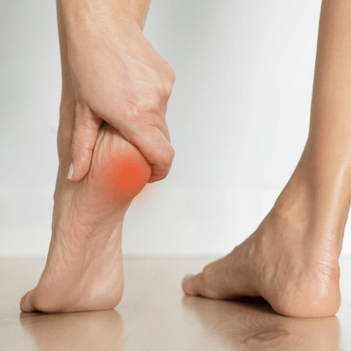 Person gripping the bottom of the heel with highlighted pain indicating heel pad syndrome.
