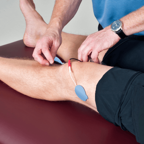 Clinician applying electrical stimulation therapy near the inner knee for pes anserine bursitis treatment.
