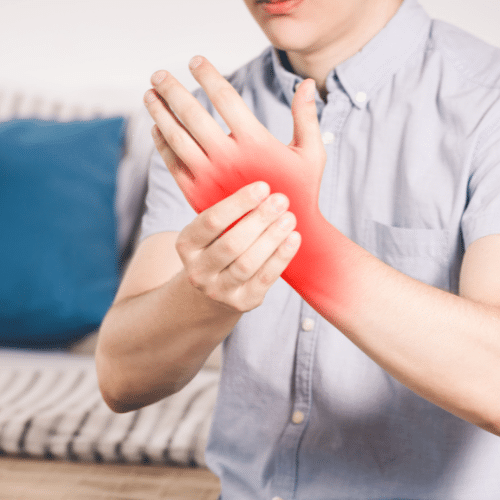 Person holding a painful wrist with highlighted pain extending into the hand, illustrating carpal tunnel syndrome symptoms.