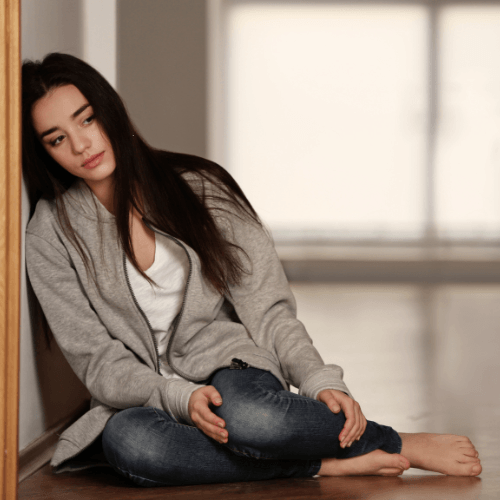 Person sitting alone with a sad expression, illustrating the emotional impact of chronic pain and depression.