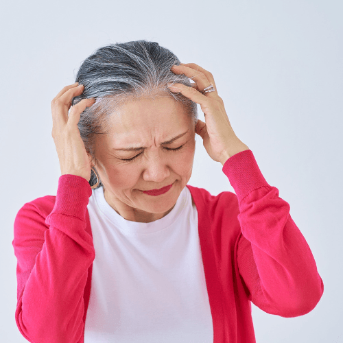 Older woman holding both sides of her head while experiencing headache pain and discomfort.