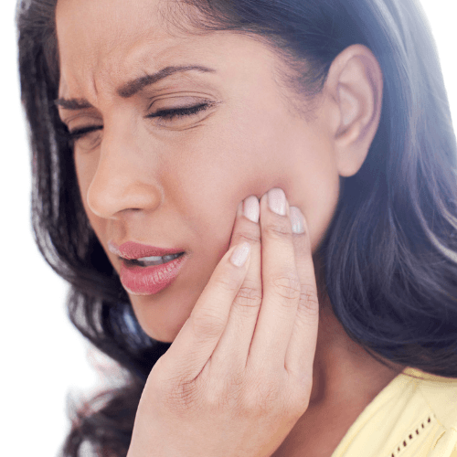 Woman holding the side of her jaw while experiencing pain associated with temporomandibular joint dysfunction (TMD).