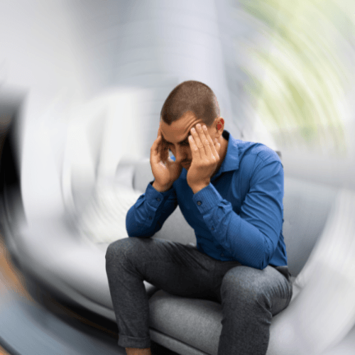 Man holding his head while experiencing dizziness and a spinning sensation associated with cervicogenic vertigo.