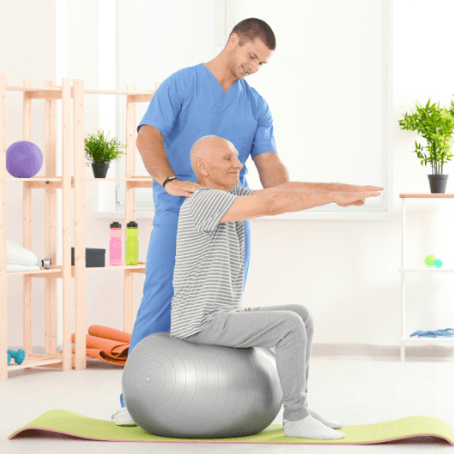 Healthcare provider guiding an older adult through a stability ball exercise during chiropractic rehabilitation for the spine and joints.