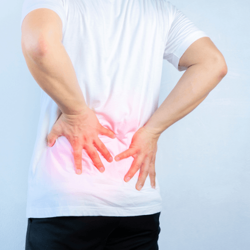 Person in a white shirt holding both hands to their lower back with the area highlighted in red